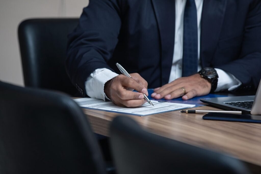 Professional signing paperwork at an office desk
