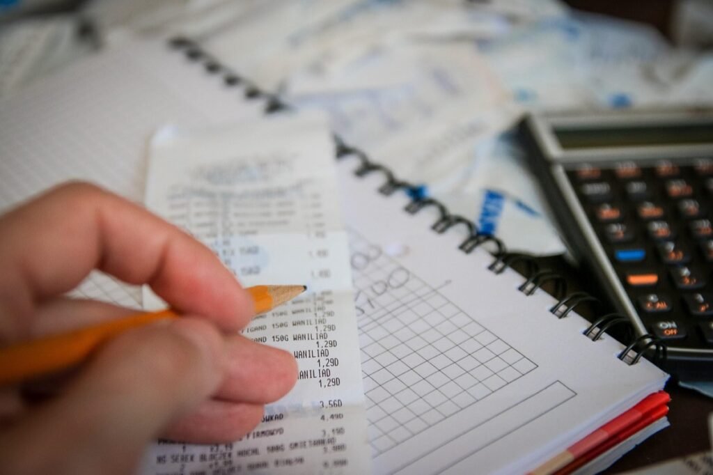 Person checking bills with a calculator and notebook