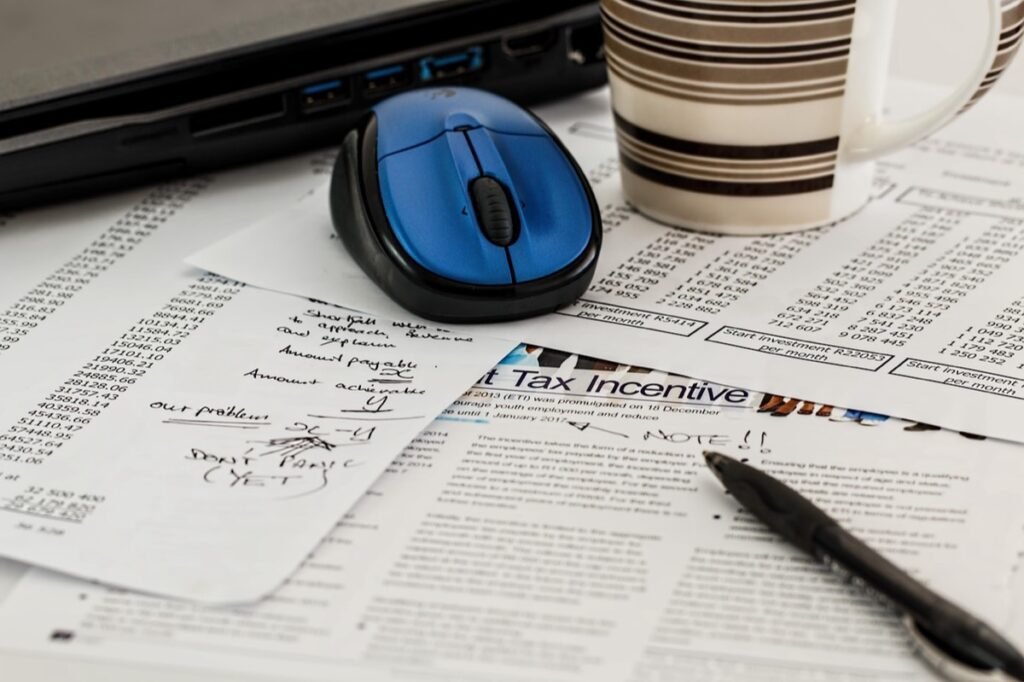 Paperwork and a pen on a desk beside a mouse and coffee mug